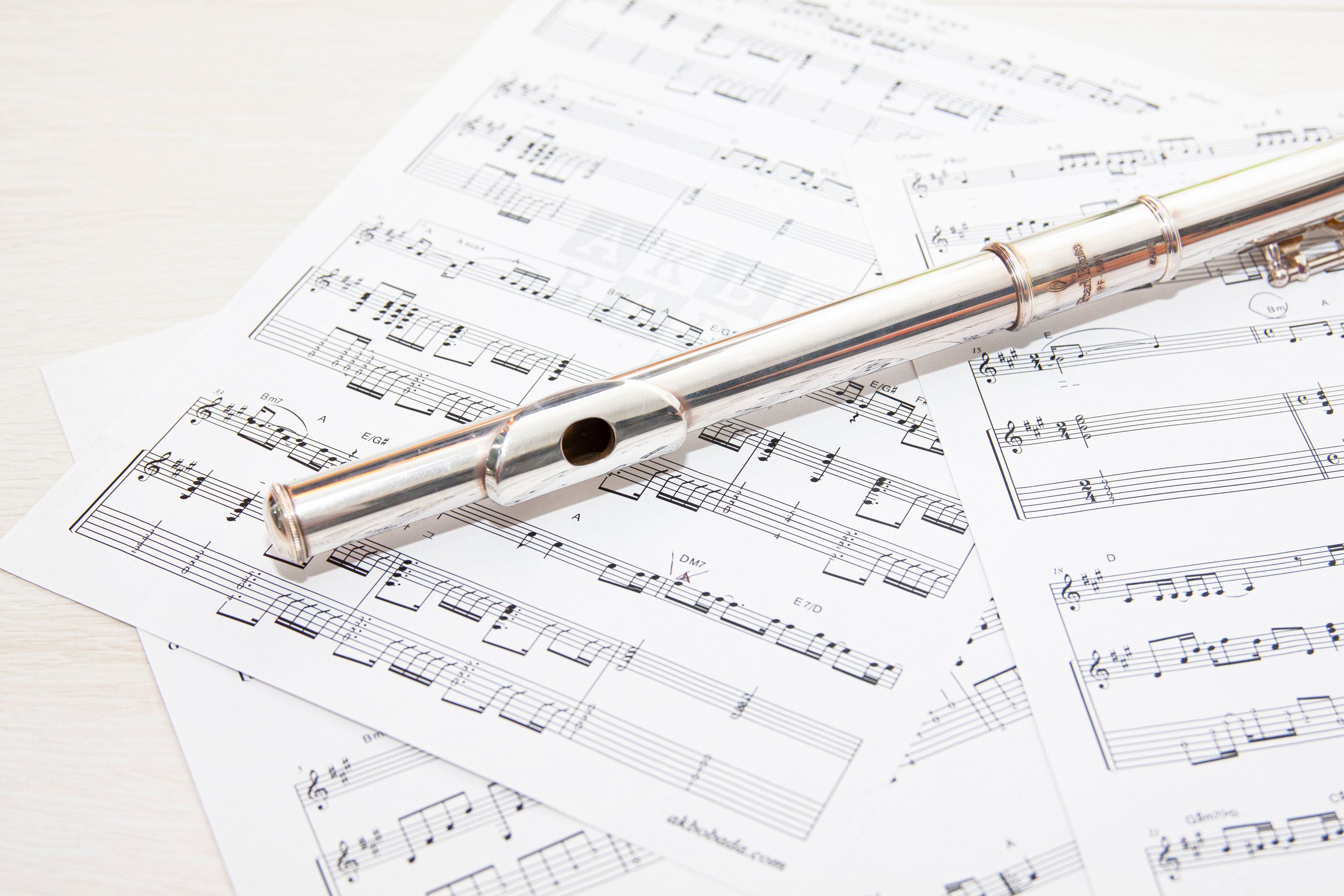 Close-Up Photo of Music Sheets with Silver Flute